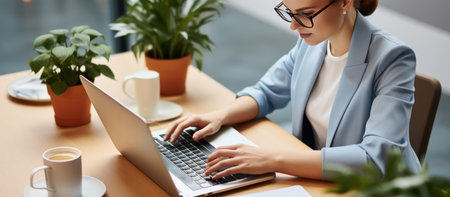 businesswoman in eyeglasses typing on laptop at workplace in officeの素材