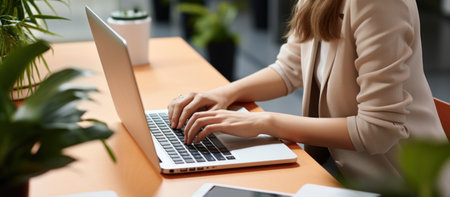 Cropped view of businesswoman typing on laptop at workplace in officeの素材