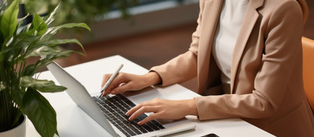 Cropped view of businesswoman working with laptop at workplace in officeの素材