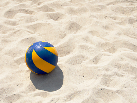 Yellow and blue volleyball on the beach sandの写真素材