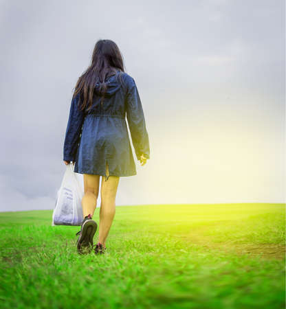 woman walking in the field with shopping bags, woman walking on a road in the fieldの写真素材