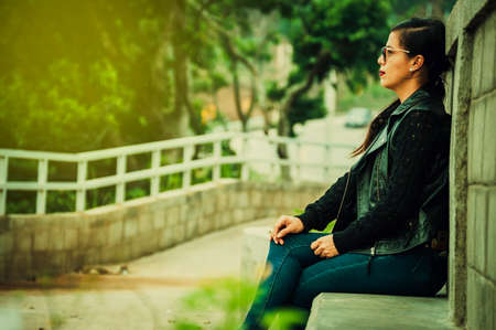 Latin girl with sitting on a bench, attractive girl with glasses sitting on a bench