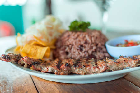 Close up of roast beef with gallo pinto and pico de gallo, Nicaraguan food served on wooden table, Plate with roast beef and rice served on wooden tableの写真素材