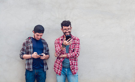 Smiling guys checking their cellphones, Smiling handsome young men checking their cellphones, Two...