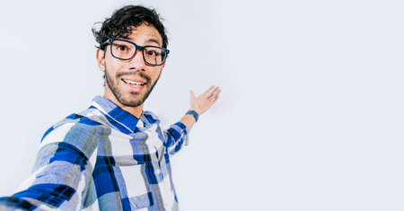 Man pointing back and presenting a product, Young man welcoming you isolated, person welcoming you with one hand. Friendly man inviting you to eatの写真素材