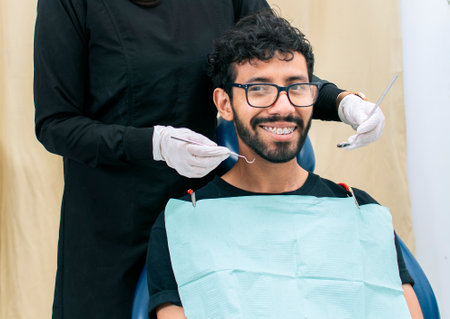 Dentist examining mouth to smiling patient, Female dentist doing root canal to female patient,...