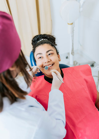 Patient lying on chair smiling at dentist, Close up of female dentist doing dental checkup to smiling patient, Dentist doing dental checkup to female patientの写真素材