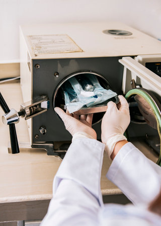 Close up of hands with dental autoclave sterilizer machine. Dentist hands sterilizing tools with autoclave, dentist with dental autoclave, close up of dentist with steam sterilizerの写真素材