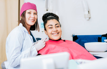 Portrait of smiling dentist with female patient in medical office, Female dentist with smiling female patient looking at camera, Professional dentist with female patient in officeの写真素材