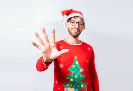 Man in christmas hat counting number five with fingers. Man in christmas costume counting number five with fingers. Concept of man in christmas costume counting number five isolatedの写真素材
