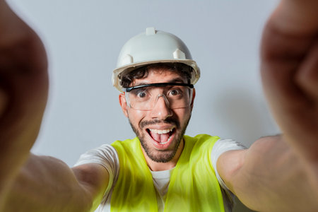 Smiling male engineer taking a selfie looking at camera. Funny builder engineer taking a selfie isolated, Engineer taking a selfie isolated. View of male engineer taking a selfie isolatedの写真素材