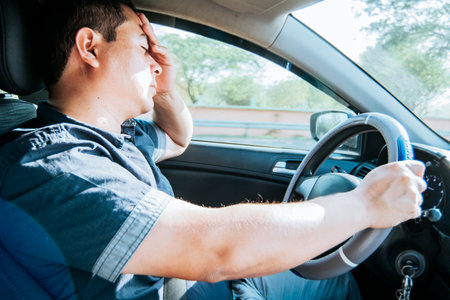 fatigued driver stuck in traffic, concept of a fatigued man in his car, stressed. A driver with a...