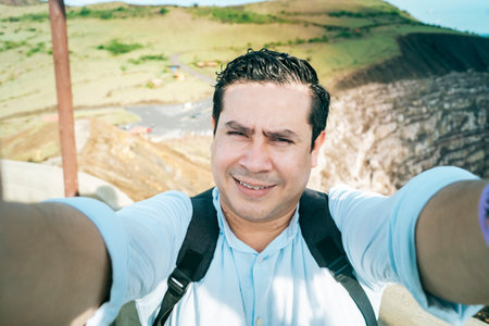 Close up of man taking an adventure selfie, Tourist taking a selfie at a viewpoint. Adventurous people taking a selfie at a viewpoint. Handsome tourist taking a selfie on vacationの写真素材