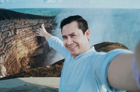 Tourist taking a selfie at a viewpoint. Handsome tourist taking a selfie on vacation. Adventurous man taking a selfie at a viewpoint. Close up of person taking an adventure selfieの写真素材