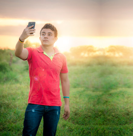 Young man taking a picture, young man taking selfie in the field, young man in the field taking a pictureの写真素材