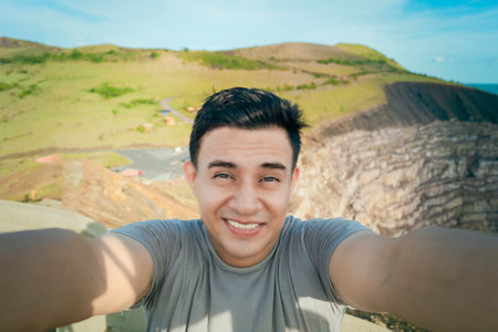 Adventurous man taking a selfie at a viewpoint. Close up of person taking an adventure selfie, Tourist taking a selfie at a viewpoint. Handsome tourist taking a selfie on vacationの写真素材