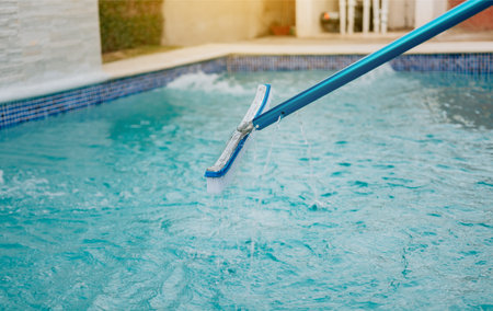 Swimming pool cleaning with brush. Pool brush for wall cleaning, Worker cleaning a pool with special brushの写真素材