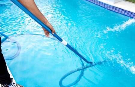 Pool maintenance and cleaning with vacuum hose. People cleaning swimming pool with suction hose. Close-up of man cleaning a swimming pool with a vacuum hoseの写真素材