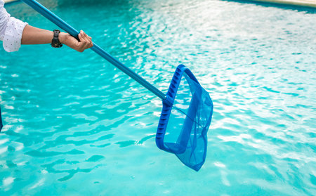 A man cleaning pool with leaf skimmer. Man cleaning the pool with the Skimmer, Person with skimmer...