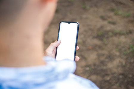 Close up of a man with cell phone in hand, close up shot of a person checking his cell phone, young guy with cell phone in hand with copy spaceの写真素材