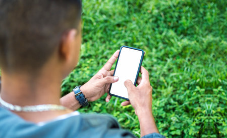 Close up of a man with cell phone in hand, close up of hands with cell phone with white screen, young guy with cell phone in hand with copy spaceの写真素材