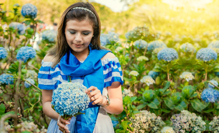 Nicaraguan girl in traditional folk costume holding flowers in a nursery. Beautiful Nicaraguan woman...