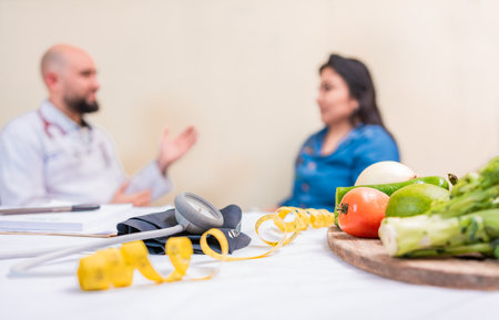 Nutritionist man with woman patient in office. Nutritionist talking to female patient with focus on the fruits in the foreground. Concept of nutritionist advising female clientの写真素材