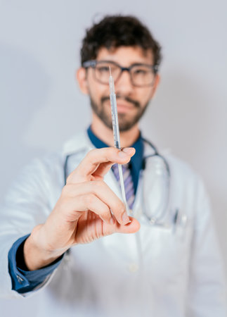 Close up of doctor holding a syringe isolated. Smiling doctor holding a syringe on isolated backgroundの写真素材