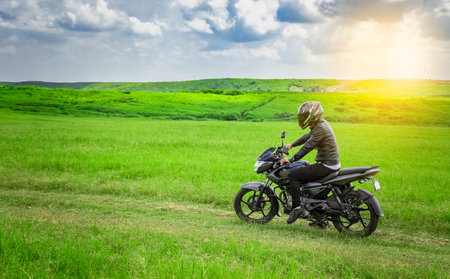 Biker man on a country road, young man on his motorcycle traveling through the countryside with copy space, man riding motorcycle in the countrysideの写真素材