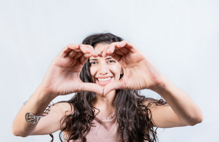 Happy girl making heart shape with hands isolated. Smiling young woman making heart shape with her hands. Teen girl making heart shape with her handsの写真素材