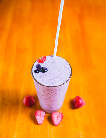 Strawberry smoothie with blueberry on wooden background. Strawberry milkshake on wooden tableの写真素材