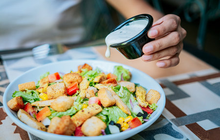 Close up of hand preparing a vegetable salad. Concept of healthy food and lifestyle, Hand putting dressing on a caesar saladの写真素材