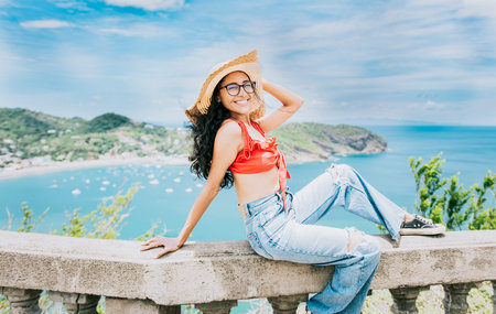 Happy tourist woman in hat on a viewpoint. Smiling vacationer girl in a viewpoint. Travel and...