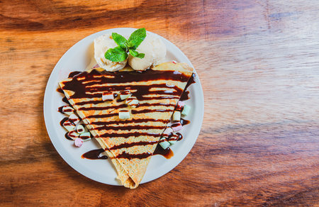 Top view of chocolate crepe with ice cream on wooden table. High angle view of chocolate crepe with ice cream on wooden backgroundの写真素材
