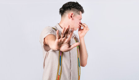Confused unhappy man grabbing nose with fingers and stretching hand out feeling disgusted, A man with covering his noseの写真素材