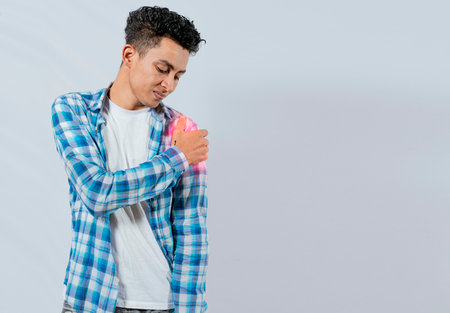 Young man with shoulder pain on white background. Shoulder and arm pain concept. People with shoulder pain on white background. Man suffering with shoulder muscle painの写真素材