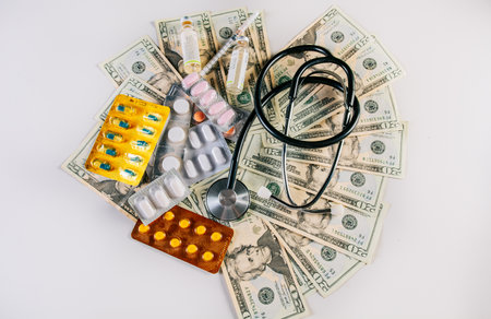 Top view of stethoscope with pills on money isolated. High cost of medical health with stethoscope and medicines. View of medical stethoscope with medications and moneyの写真素材