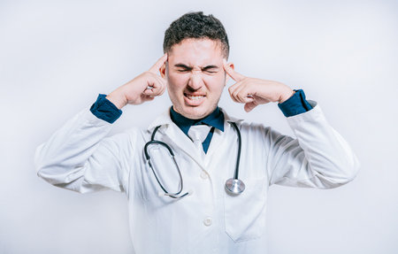 Doctor with migraine holding his head. Fatigued doctor with headache isolated, Young Doctor with headache isolatedの写真素材