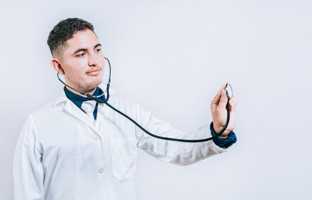 Male doctor holding stethoscope on white background. Portrait of latin doctor holding stethoscope with copy spaceの写真素材