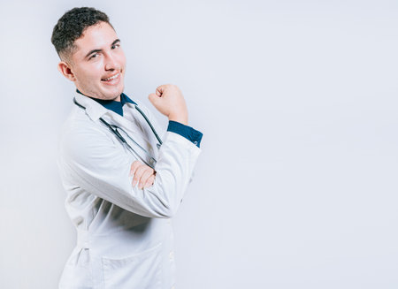 Doctor showing muscle and smiling isolated. Young doctor showing strength with his armの写真素材