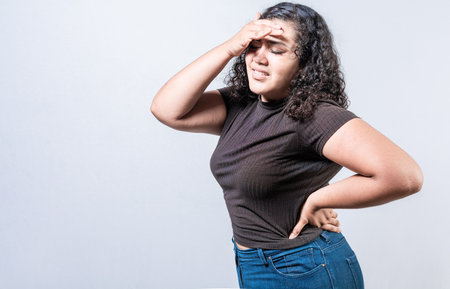 Worried young woman holding her forehead. Worried girl isolated. Tired woman holding her headの写真素材