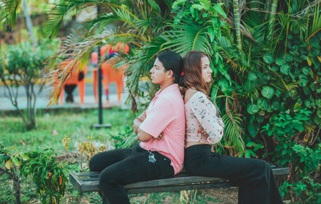 Upset young couple sitting back to back on a bench. Unhappy couple arguing on a public bench. Concept of couple problems and crisisの写真素材