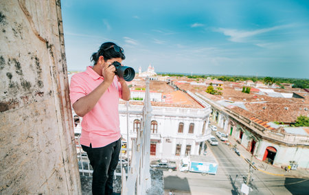 Tourist photographing the streets of Granada from the La Merced viewpoint. Tourist man taking photos of the roof of the colonial houses in Granadaの写真素材