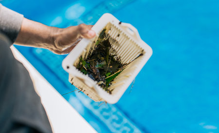 Man cleaning garbage filter basket for swimming pool. Trash. Hand holding swimming pool filter basketの写真素材
