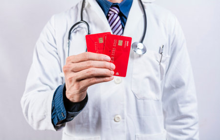 Doctor hands holding credit cards. Doctor holding two credit cards isolated. Concept of medical card paymentsの写真素材