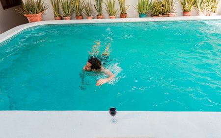 Young man swimming in a tropical hotel pool. Handsome man on vacation swimming in a hotel pool, Man...