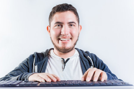 Portrait of nerdy man in front of keyboard. Smiling nerdy guy with hands on keyboard smiling at cameraの写真素材
