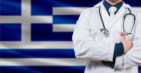 Male doctor with stethoscope on Greece flag. Doctor holding stethoscope on Greek flagの写真素材