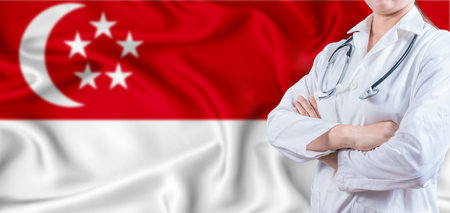 Doctor with crossed arms on Singapore flag. Singapore Health and Care concept. Female doctor on Singapore flagの写真素材