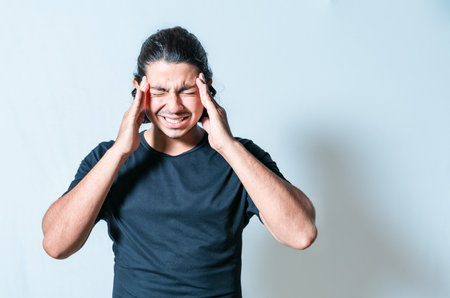 Headache and migraine concept. Suffering man with migraine massaging head isolatedの写真素材